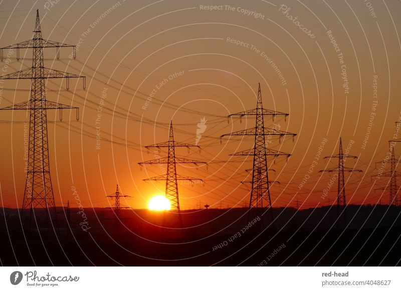 Hochspannungsmasten vor orangerotem Abendhimmel, Sonne berührt Horizont hinter Strommast Energie Sonnenuntergang Stromleitung Hochspannungsleitung Abendsonne