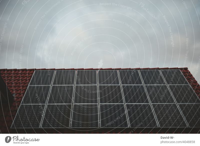 Solarzellen auf einem Dach bei bedecktem Himmel Photovoltaik Photovoltaikanlage grau düster schlechtes Wetter Wolken Solarenergie Erneuerbare Energie