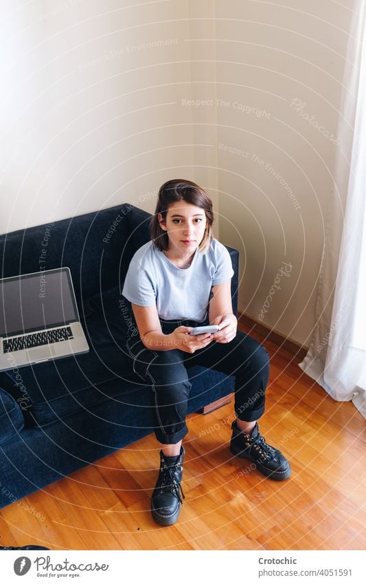 Mädchen tippt auf der Zelle in ihrem Sofa mit ihrem geflügelten Laptop Person Frau Glück jung Liege heimwärts Tippen Technik & Technologie Mitteilung Sitzen