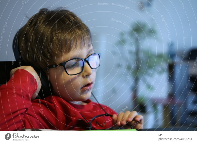 Kind trägt eine Brille und hört einen Kopfhörer Sicherheit Seuche Quarantäne zuhören Musik Familienzeit Musik hören Technik & Technologie Vernehmung Erholung