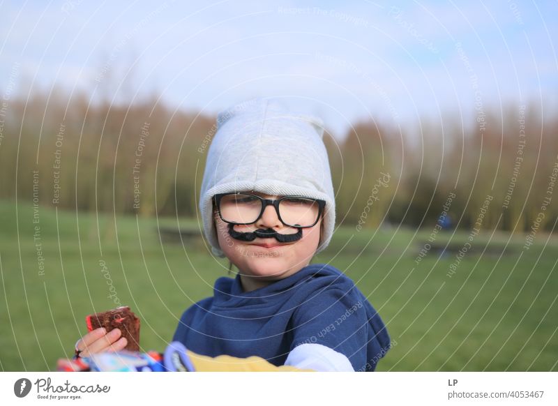 kleines Kind mit Brille, Hut und falschem Schnurrbart Blick Porträt mehrfarbig geheimnisvoll Gefühle lustig Oberlippenbart Mode Gesicht Jugendliche Kindheit