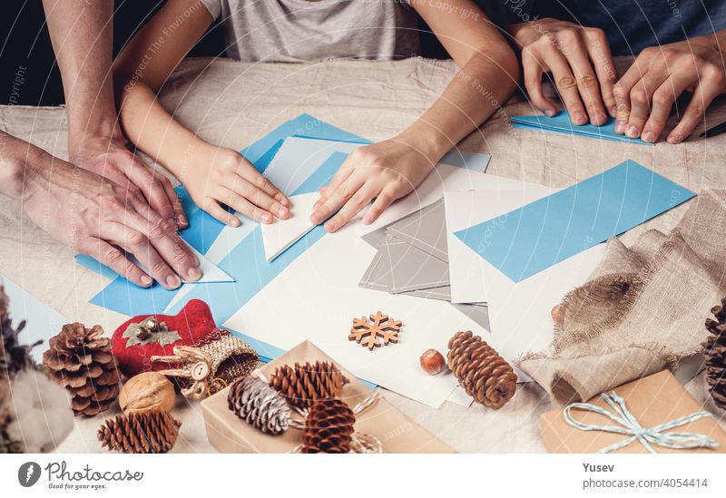 Hände einer kaukasischen Mutter und ihre Tochter sind Schneiden Papier Schneeflocken mit Schere. Handmade, Weihnachtsschmuck, Familie Winter Aktivität. Nahaufnahme. Banner-Format