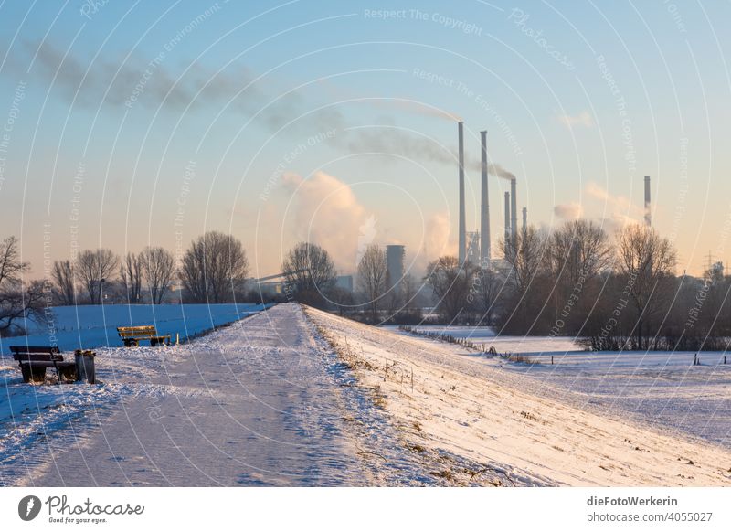 Blick über einen verschneiten Deich auf Industrie Bank Fahrbahn Fluchtlinien Hell Himmel Natur Schnee Sonnenaufgang Technologie Weg Winter Wolken dampf qualm