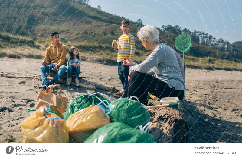 Freiwillige, die sich nach der Reinigung des Strandes ausruhen Müllsäcke Freiwilliger Menschengruppe Familie Essen aussruhen pausieren Pause Lächeln Reinigen