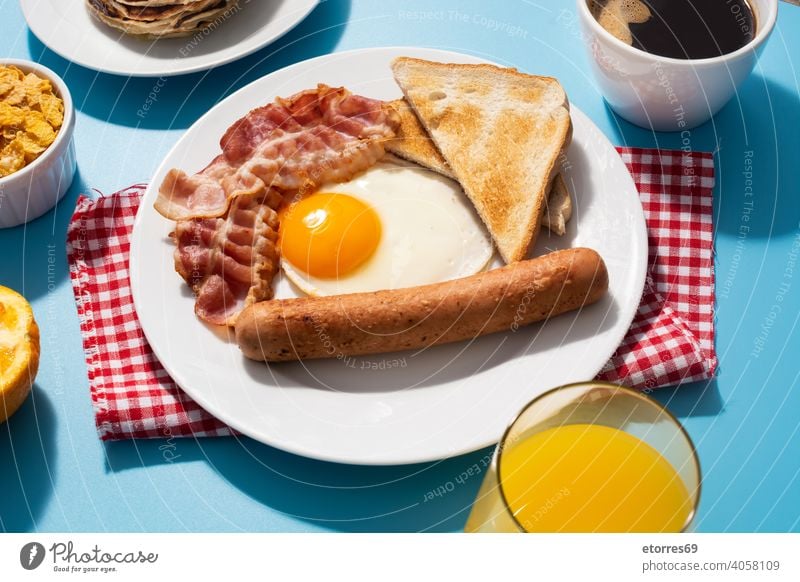 Traditionelles amerikanisches Frühstück auf blauem Hintergrund amrican Speck Brot Butter Zerealien Speise Ei Fett Lebensmittel gebraten Frucht Saft Ernährung