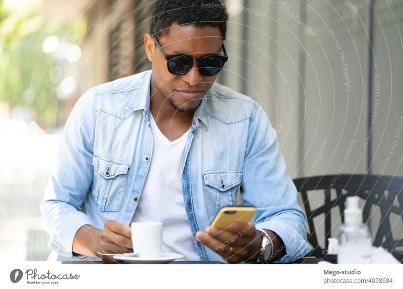Mann benutzt sein Mobiltelefon in einem Café. Mobile Telefon urban Großstadt Afrikanisch Amerikaner Kaffeehaus Technik & Technologie Smartphone sozial Medien