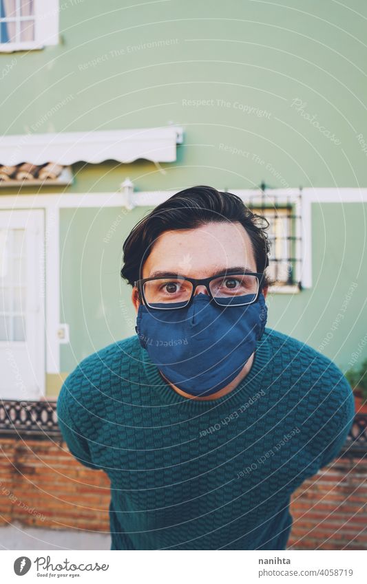 Junger Mann mit Gesichtsmaske vor einer grünen Wand Porträt männlich COVID Coronavirus Brille Grippe influencia Risiko verantwortlich Gesundheit Augenabnutzung