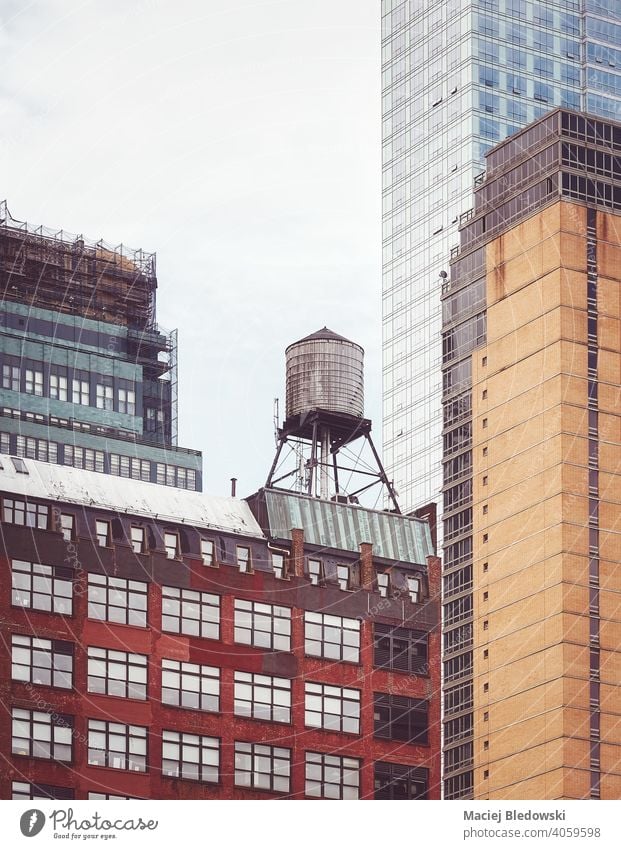 Alter Wasserturm, eines der Symbole von New York City, inmitten von modernen Gebäuden, aufgetragene Farbtonung, USA. Großstadt New York State Wassertank