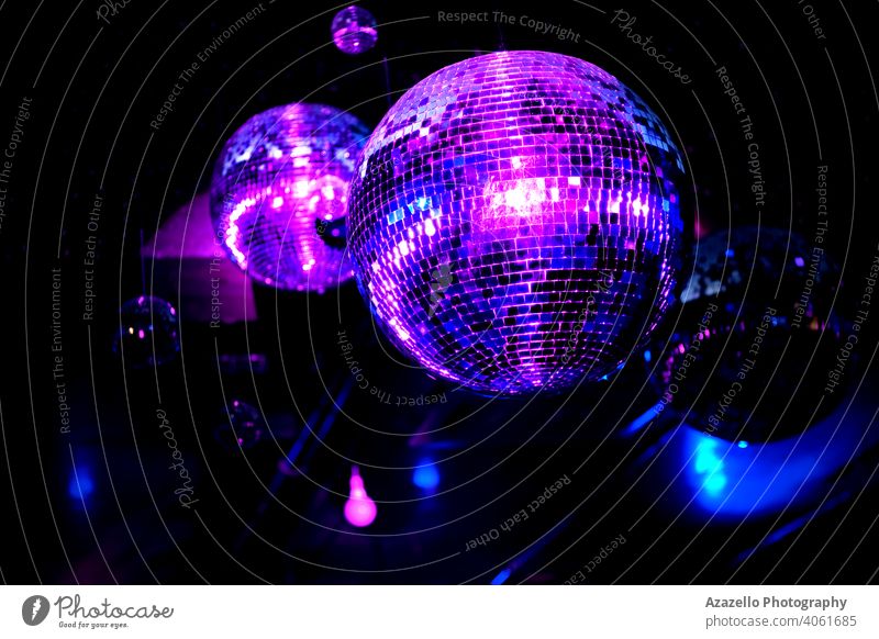 Disco-Kugel in einem Nachtclub in blauen und lila Lichtern. Spiegelkugel mit Reflexionen und Strahlen. abstrakt Hintergrund Ball hell Feier Club farbenfroh cool