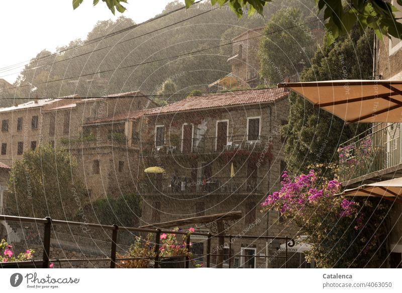 Ein erfrischender Regenschauer geht nieder über das Dorf am Berg Tageslicht Berge Dach Architektur Gebäude Häuser Baum Wolken Himmel Sonnenschirm nass Straße