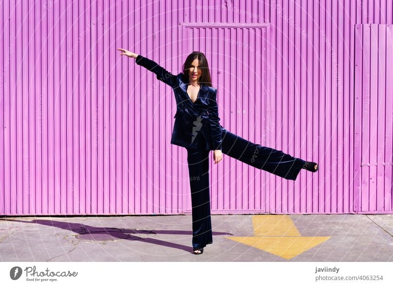 Frau im blauen Anzug tanzt in der Nähe eines rosa Rollladens. Mädchen Waffen Tanzen Bein Person Mode Model Lifestyle urban Hintergrund Dame elegant Gebäude