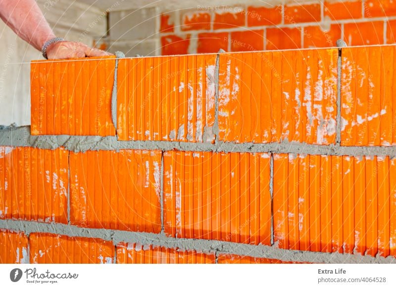 Arbeiter baut Mauer mit roten Blöcken und Mörtel Genauigkeit genau Aktivität Architektur Klotz Baustein Maurer Maurerarbeiten Mauerwerk Bauherr Baustelle