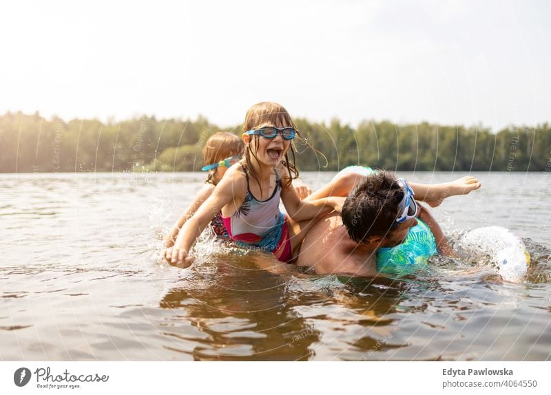 Vater und Kinder haben Spaß im See Sommer Urlaub reisen Wasser Lachen Tag sonnig platschen Tropfen Spielen spielerisch aktiv Strand schön Kindheit Familie
