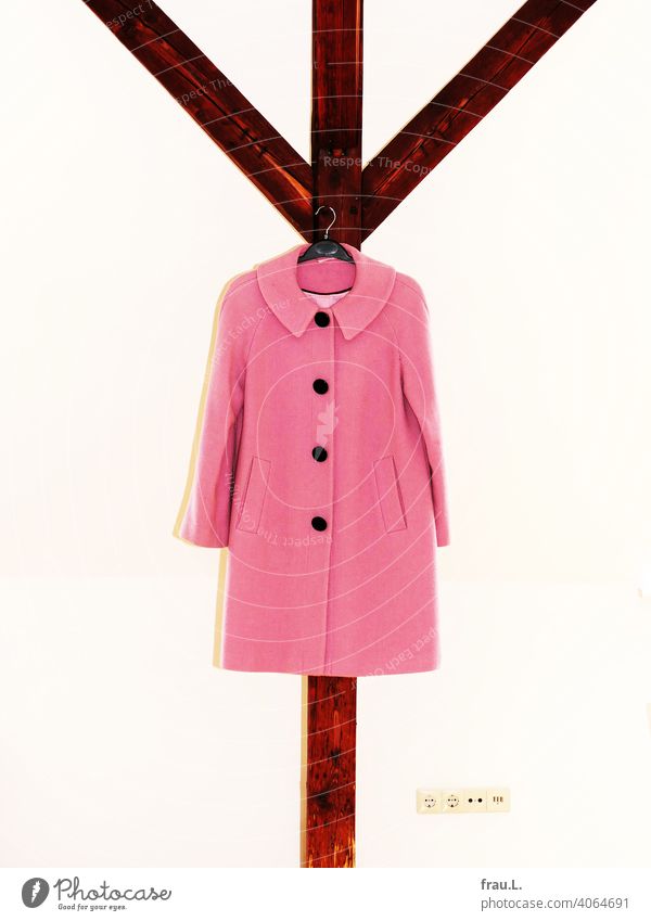 Ein rosa Mantel hängt am Dachbalken Stützbalken Innenaufnahme Mode Wintermantel Steckdose Wand Blitzlichtaufnahme Damenmode