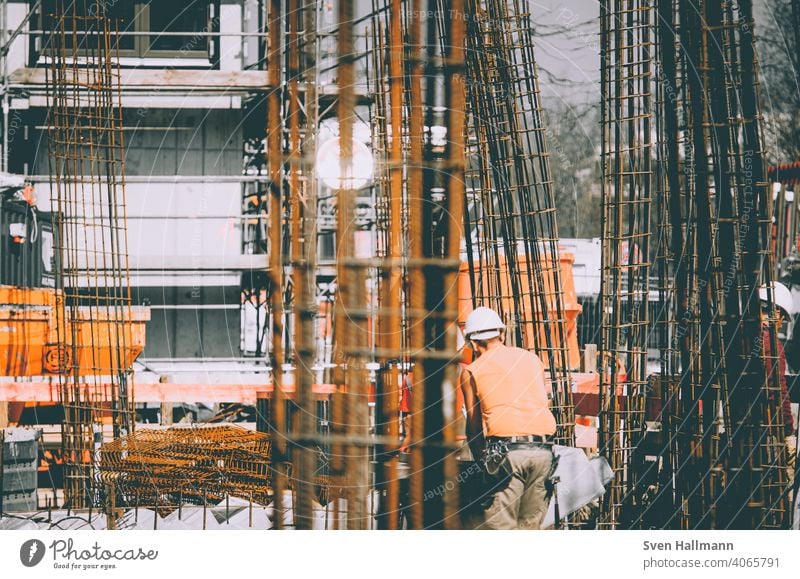 Bauarbeiter neben Stahlträgern Baustelle Stahlträger orange baum handwerker mann Architektur bauen Bauwerk Gebäude Metall Kran Gerüst Arbeit & Erwerbstätigkeit