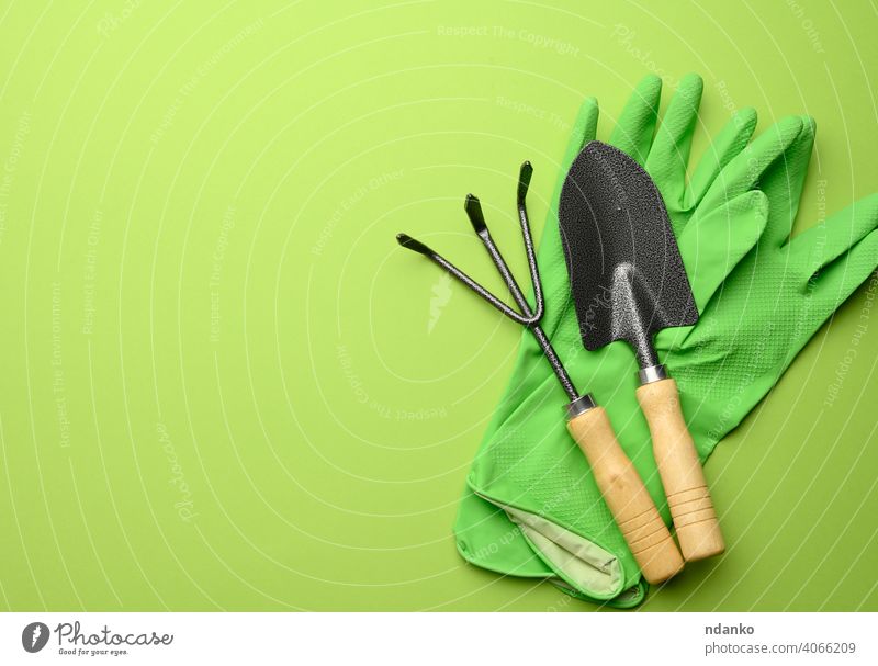 grüne Gummihandschuhe und Garten-Set von Schaufeln, Harken, Mistgabeln auf einem grünen Hintergrund Gabel Ackerbau Gerät Gärtner Gartenarbeit Handschuh
