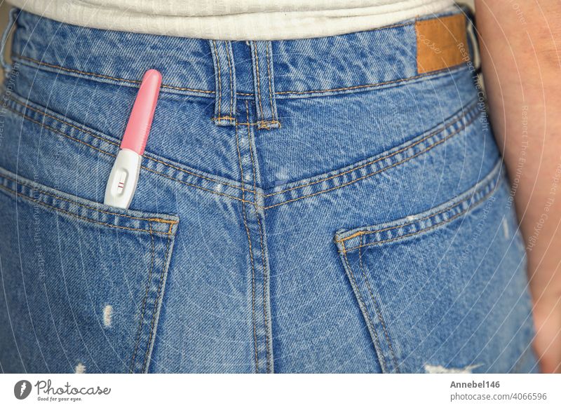 Junge Frau mit positivem Schwangerschaftstest in der Tasche einer Jeans Großaufnahme Jeanshose jung Warten Überraschung schwanger Mutterschaft Beteiligung