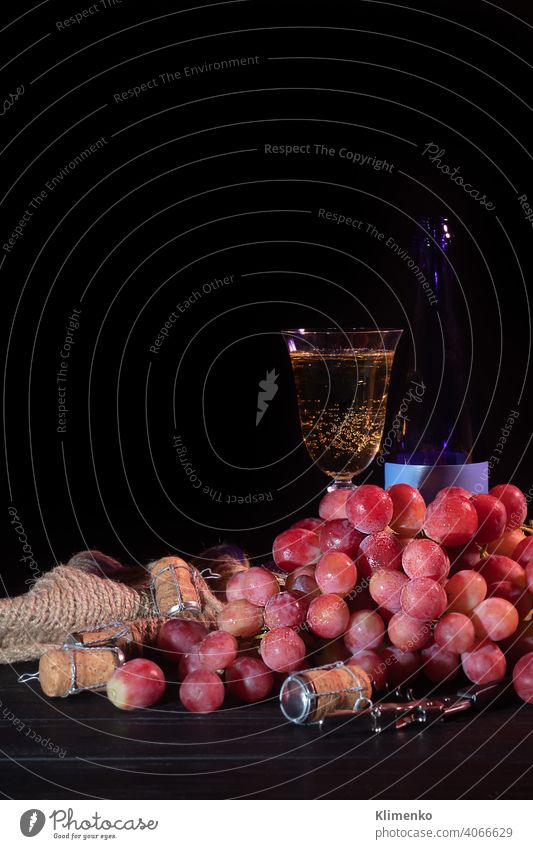 Trauben von rosa Trauben und grünen Äpfeln auf einem dunklen Hintergrund. Ein Glas Champagner steht im Hintergrund. Stilleben. Vitamin-Korb. Apfel Stillleben