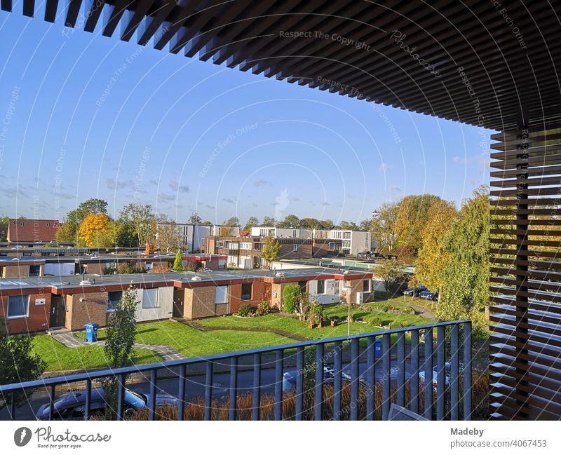 Blick vom Balkon einer Ferienwohnung in einem modernen Apartmenthaus auf eine Siedlung mit Bungalows für Touristen im Grünen bei Sonnenschein in Bensersiel bei Esens an der Küste der Nordsee in Ostfriesland in Niedersachsen