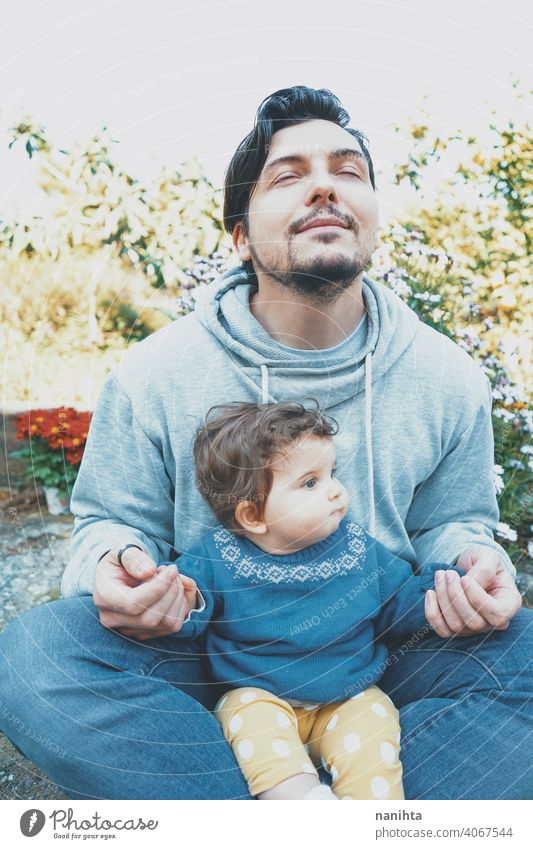 Junger Vater genießt einen sonnigen Tag mit seinem Baby im Garten Papa Familie Liebe Fröhlichkeit Yoga Meditation Atmung Übungen Pflege fürsorglich
