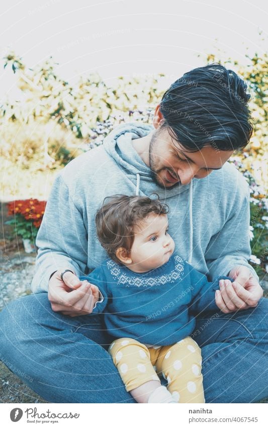 Junger Vater genießt einen sonnigen Tag mit seinem Baby im Garten Papa Familie Liebe Fröhlichkeit Pflege fürsorglich Kindererziehung lieblich niedlich im Freien