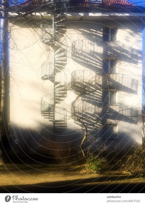 Eine Wendeltreppe und ihr Schatten außen brandmauer fassade fenster haus himmel himmelblau hof innenhof innenstadt mehrfamilienhaus menschenleer mietshaus