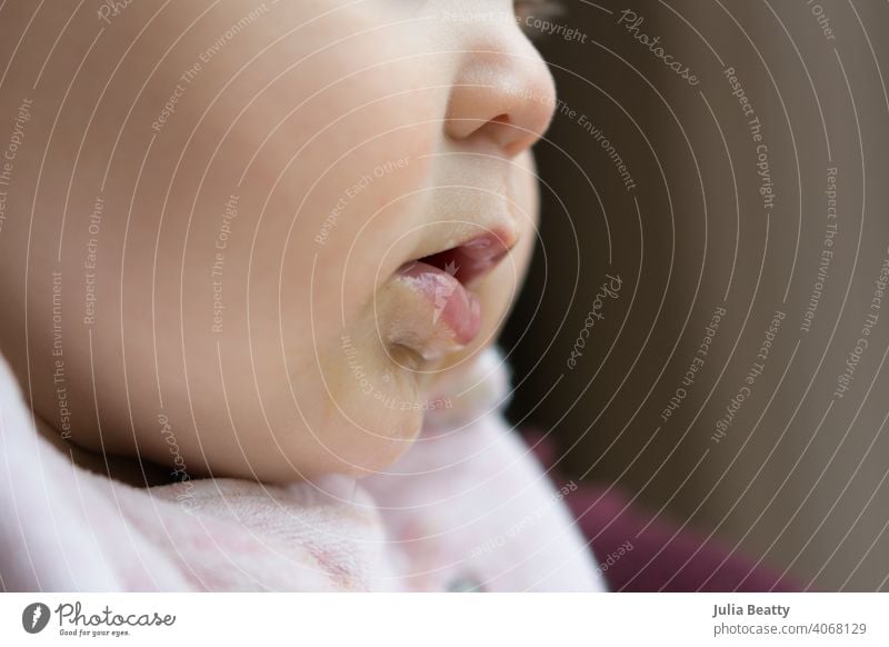 Profil des Gesichts eines jungen Babys; das Baby zahnt und sabbert, während es aus dem Fenster schaut zahnend sabbern Kind niedlich Junge neugeboren Porträt