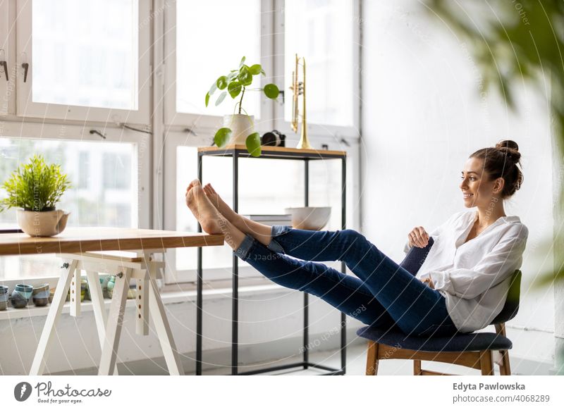 Junge Frau entspannt im Büro mit ihren nackten Füßen auf dem Schreibtisch Jahrtausende Schüler Hipster im Innenbereich Loft Fenster natürlich Mädchen