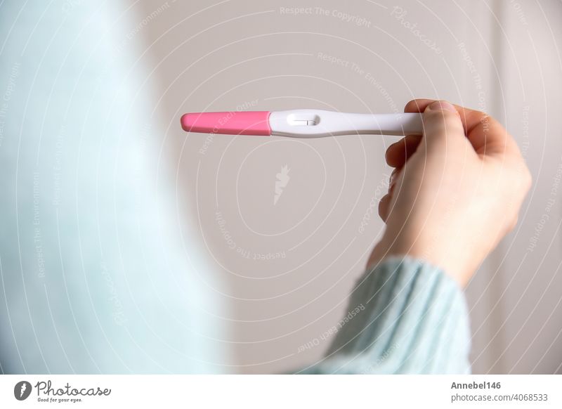 Junge Frau hält negativen Schwangerschaftstest, Schwangerschaftstest zu Hause zeigt negatives Ergebnis Nahaufnahme schwanger Prüfung medizinisch Fruchtbarkeit