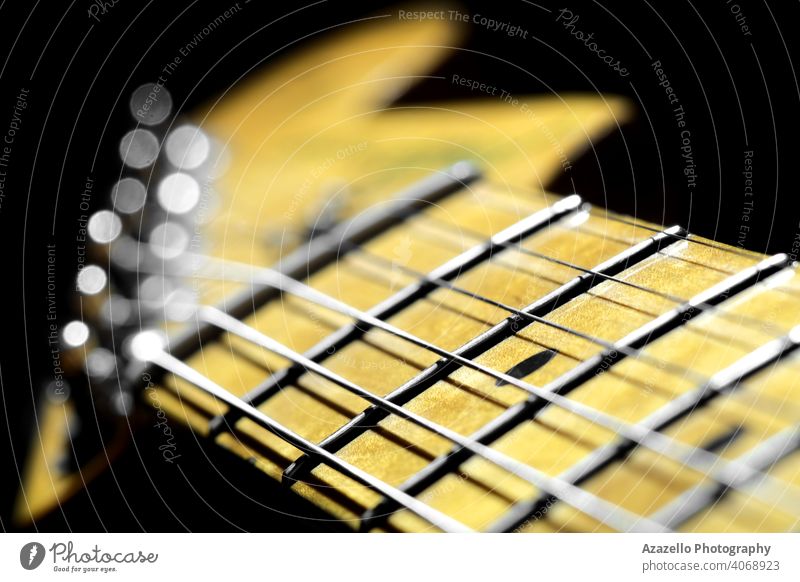 Griffbrett einer E-Gitarre mit einer Kopfplatte in Unschärfe. Ahorn Gitarre Hals Ansicht. Aktivität zielen Ehrgeiz Hintergrund schwarz Blues Holzplatte