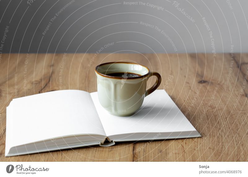 Eine rustikale Kaffeetasse auf einem offenen Buch Tasse Getränk Kaffeepause Frühstück aromatisch Morgen heiß braun alt Koffein Espresso Tisch Emaille schwarz