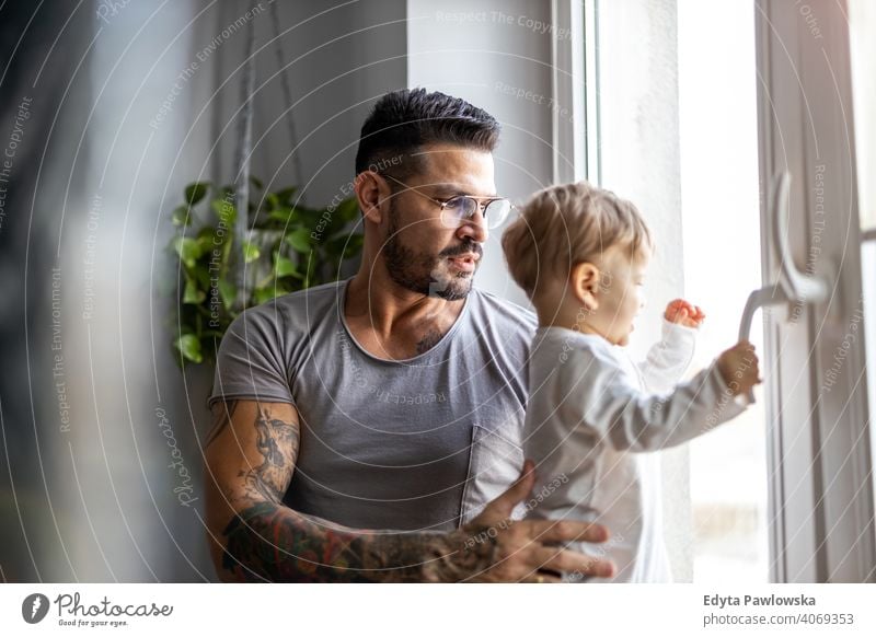 Mann mit seinem kleinen Sohn schaut durch das Fenster zu Hause alleinerziehend alleinerziehender Vater Vatertag Vaterschaft zu Hause bleiben Dad