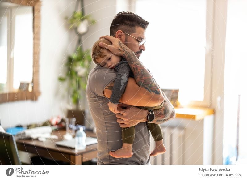 Papa legt Baby in seinen Armen zu Hause schlafen alleinerziehend alleinerziehender Vater Vatertag Vaterschaft zu Hause bleiben Dad Vaterschaftsurlaub