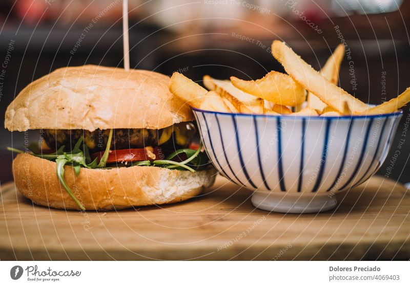 Rindfleisch-Burger mit Cheddar-Käse und handwerklichem Brot, gefüllt mit Tomate, Rucola, Mayonnaise. Cholesterin Tisch Holzplatte Ketchup isoliert Textfreiraum