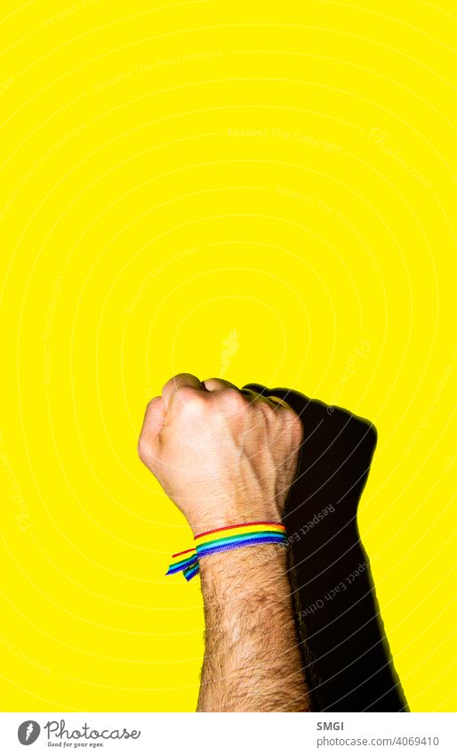 Die hochgehaltene Faust eines Mannes mit einem Armband in den Farben der schwulen Flagge. feiern Feier farbenfroh Gemeinschaft Diskriminierung Vielfalt gleich