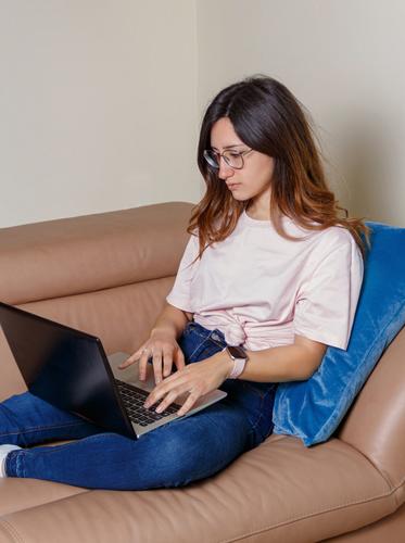 Junge Frauen verwenden einen Laptop, während sie zu Hause auf dem Sofa sitzen jung anhaben Attrappe T-Shirt lernen Schüler Lifestyle Jeanshose Brille ernst