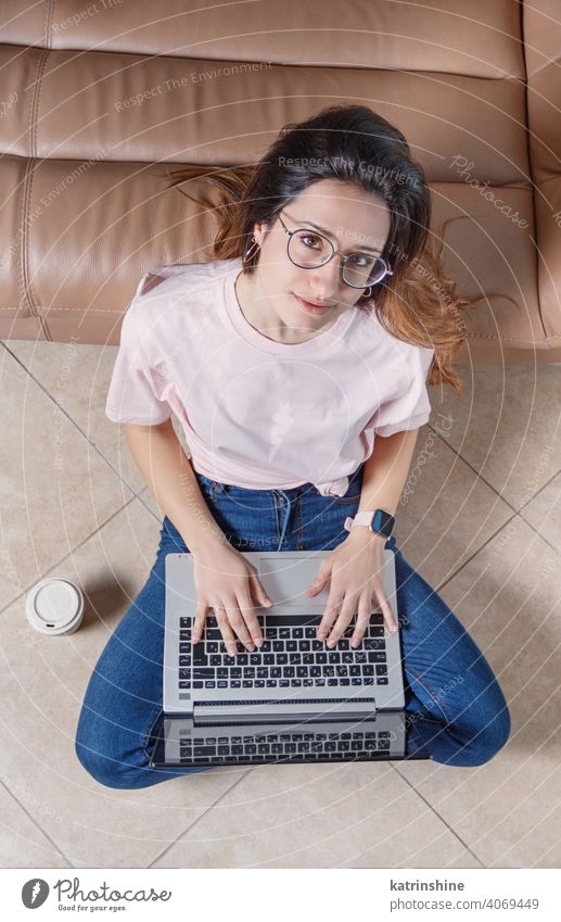 Junge Frauen verwenden einen Laptop, während sie zu Hause auf dem Boden sitzen jung anhaben Attrappe T-Shirt lernen Schüler Lifestyle Stock Jeanshose Brille