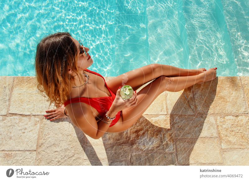 Junge Frau im roten Badeanzug mit tropischem Cocktail Mojito Pool Wasser einteilig Sommer Draufsicht jung Kaukasier Mode allein Glück Lächeln Garten Emotion