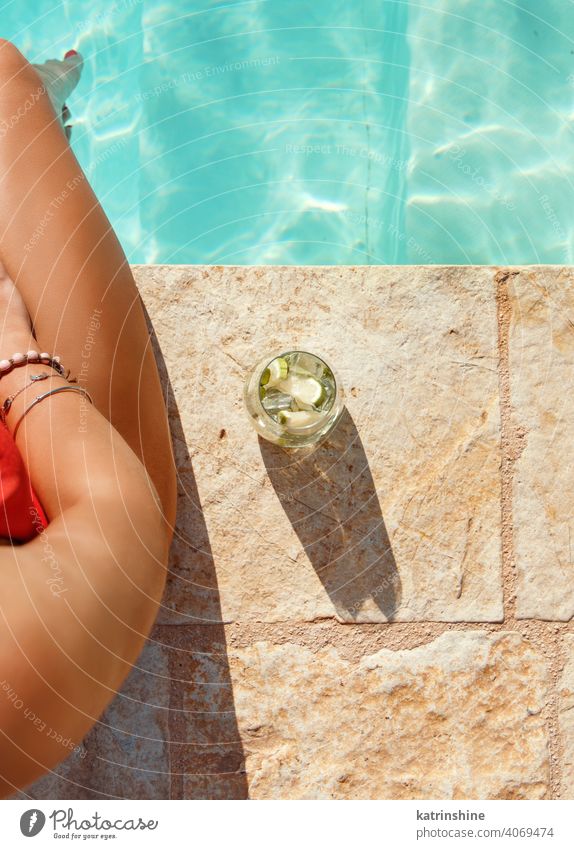 Junge Frau im roten Badeanzug mit tropischem Cocktail Draufsicht Mojito Pool gesichtslos Beine Wasser einteilig Sommer jung Kaukasier Mode allein Glück Lächeln