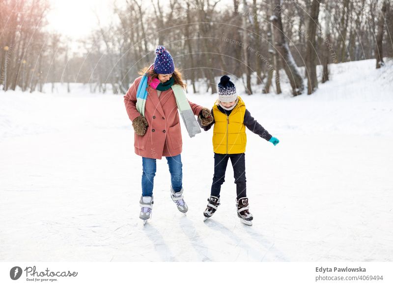 Mutter und Sohn beim Schlittschuhlaufen auf gefrorenem Teich Tochter Saison Zusammensein heiter Spaß Kind Menschen Park Feiertag Wald Kindheit Frau Mädchen