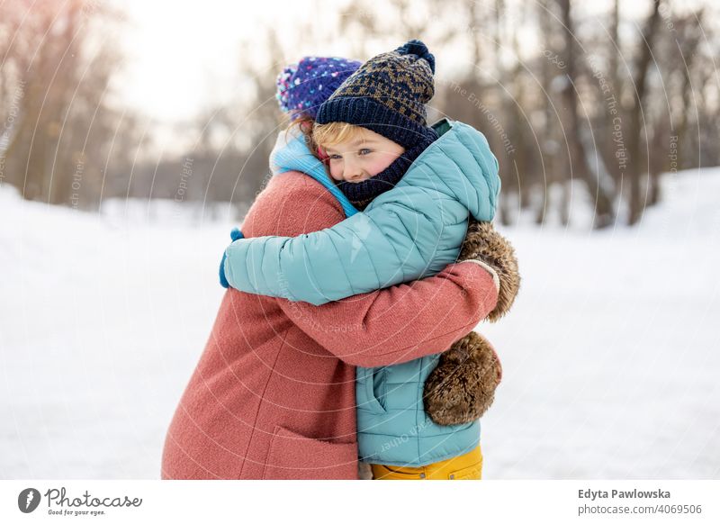 Mutter und Sohn umarmen im Freien im Schnee Tochter Saison Zusammensein gefroren heiter Spaß Kind Menschen Park Feiertag Wald Kindheit Frau Mädchen Natur Freude