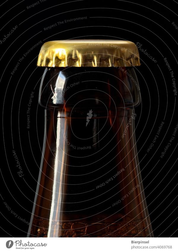 Mit einem Kronenkorken verschlossene Bierflasche Kronkorken Flasche Verschluss Zacken Blech Glas golden braun Getränk trinken Großaufnahme ungeöffnet luftdicht