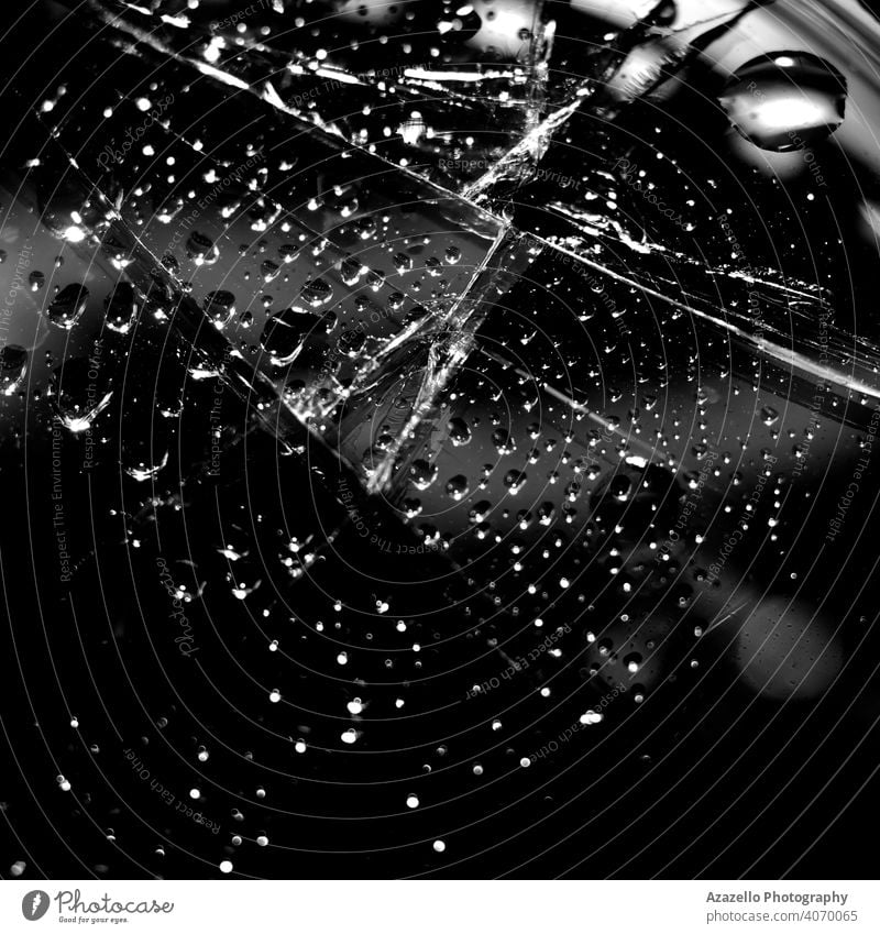 Schwarzer abstrakter Hintergrund mit Wassertropfen auf einem gesprungenen Glas. 2020 abstrakte Kunst Strahl schwarz auf weiß schwarzer Hintergrund