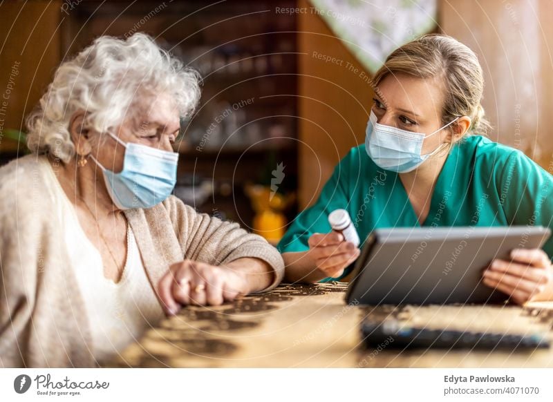 Hauspflegerin hilft Seniorin mit Medikamenten Coronavirus Gesichtsmaske echte Menschen COVID Krankenpfleger älter besuchen offen Frau reif Kaukasier heimwärts