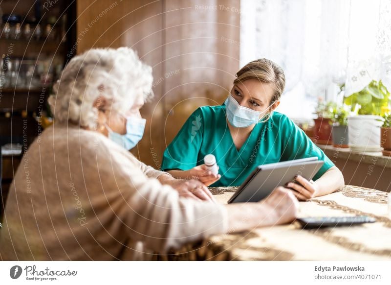 Hauspflegerin hilft Seniorin mit Medikamenten Coronavirus Gesichtsmaske echte Menschen COVID Krankenpfleger älter besuchen offen Frau reif Kaukasier heimwärts