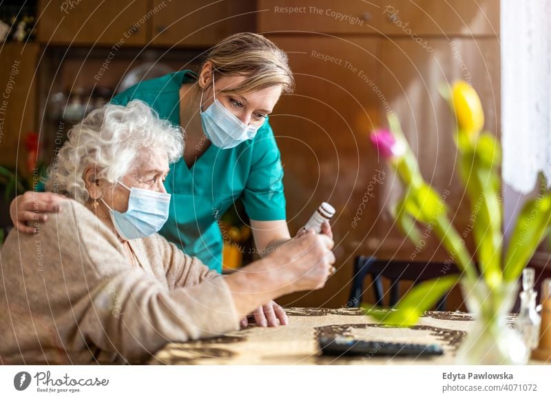 Ältere Frau wird während des Einschlusses von einer Pflegefachkraft besucht Coronavirus Gesichtsmaske echte Menschen COVID Senior Krankenpfleger älter besuchen