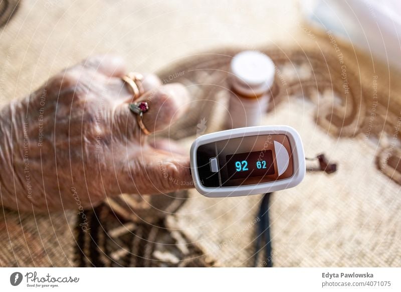 Oximeter zur Überprüfung der Sauerstoffsättigung im Blut an der Hand einer älteren Frau echte Menschen offen Senior reif Kaukasier heimwärts Haus alt Alterung