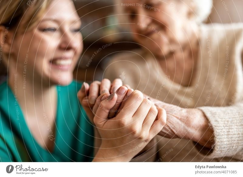 Ausgeschnittene Aufnahme einer älteren Frau, die mit einer Krankenschwester Händchen hält Hände tröstlich Händchenhalten knittern echte Menschen offen Senior