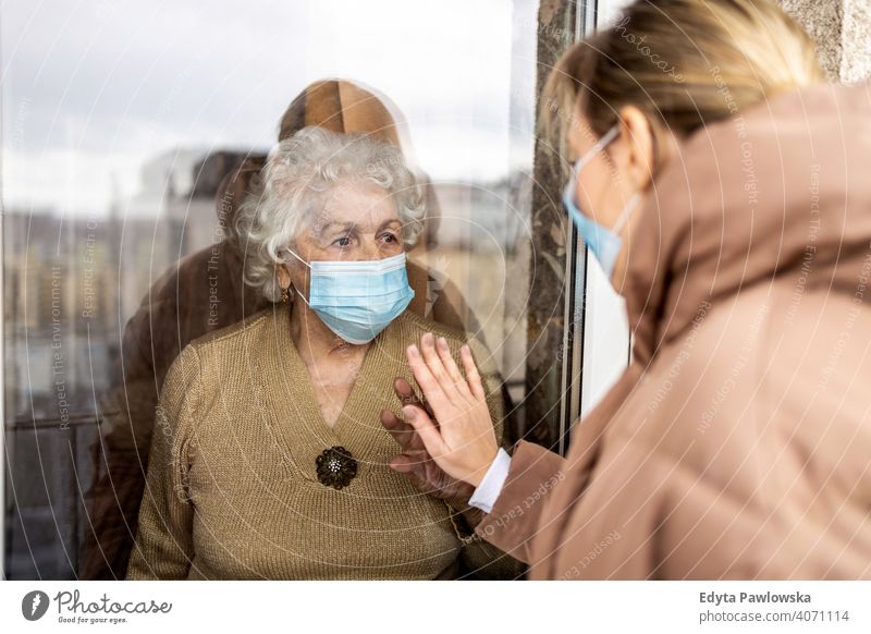 Frau besucht ihre Großmutter in der Isolation während einer Coronavirus-Pandemie Fenster COVID Sperrung Blick Quarantäne Blick durch das Fenster