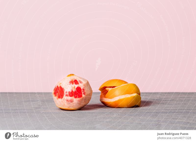 Stillleben einer geschälten Grapefruit mit der Schale daneben auf einem rosa Hintergrund sich[Akk] schälen Frucht natürlich saisonbedingt minimalistisch
